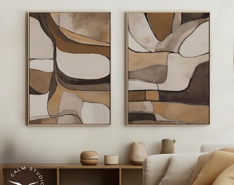 May include: Two abstract paintings in brown, beige, and white tones. The paintings are framed in a light wood frame and are hung on a white wall. The paintings are in a living room setting with a couch, a coffee table, and a shelf.