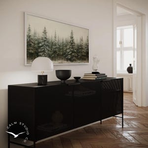 Puede incluir: Un mueble negro perforado con una pintura de bosque enmarcada encima. Una l&aacute;mpara blanca y negra, un cuenco negro y libros encima. El mueble tiene patas negras y el texto "CALM STUDIO CO." es visible.