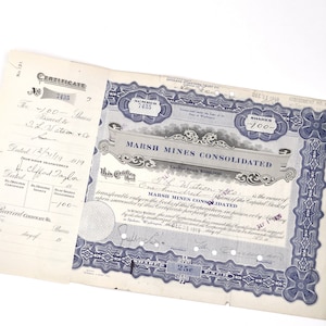 May include: A blue and white stock certificate for 100 shares of Marsh Mines Consolidated, dated December 31, 1919. The certificate number is 7435. The certificate is signed by F.L. Watson, the secretary of the company.