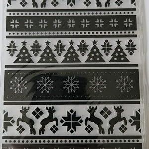 May include: A sheet of black and white Christmas-themed stickers. The design features repeating patterns of reindeer, snowflakes, Christmas trees, and geometric shapes. The stickers are arranged in horizontal bands.