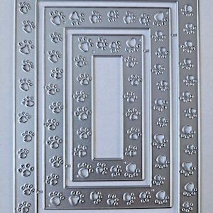 May include: A set of silver metal nested frames with paw print cutouts. The frames are rectangular and have varying sizes, with the paw prints evenly spaced along the edges. The design is suitable for pet-themed crafts.