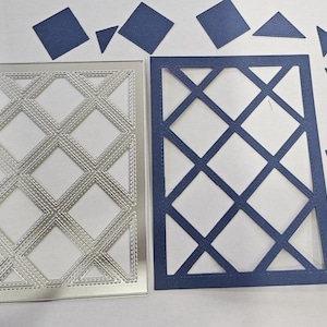 May include: Two rectangular die-cut paper designs with a lattice pattern, one in silver and the other in navy blue. Scattered around are navy blue geometric shapes, including squares and triangles, likely for crafting or scrapbooking.