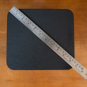 K&ouml;nnte beinhalten: Eine schwarze quadratische Oberfl&auml;che mit einem silbernen Lineal, das diagonal &uuml;ber sie gelegt ist und 76 cm (30 Zoll) misst.