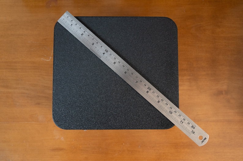 K&ouml;nnte beinhalten: Eine schwarze quadratische Oberfl&auml;che mit einem silbernen Lineal, das diagonal &uuml;ber sie gelegt ist und 76 cm (30 Zoll) misst.