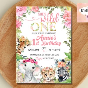 May include: A pink and gold first birthday party invitation with a jungle theme. The invitation features a giraffe, elephant, lion, and zebra with floral headbands. The text on the invitation reads "She's a wild one, Annie's 1st Birthday, Saturday Oct 15 at 4:00pm, 123 Anywhere St. Any City, ST 12345, RSVP (123) 456-7890".