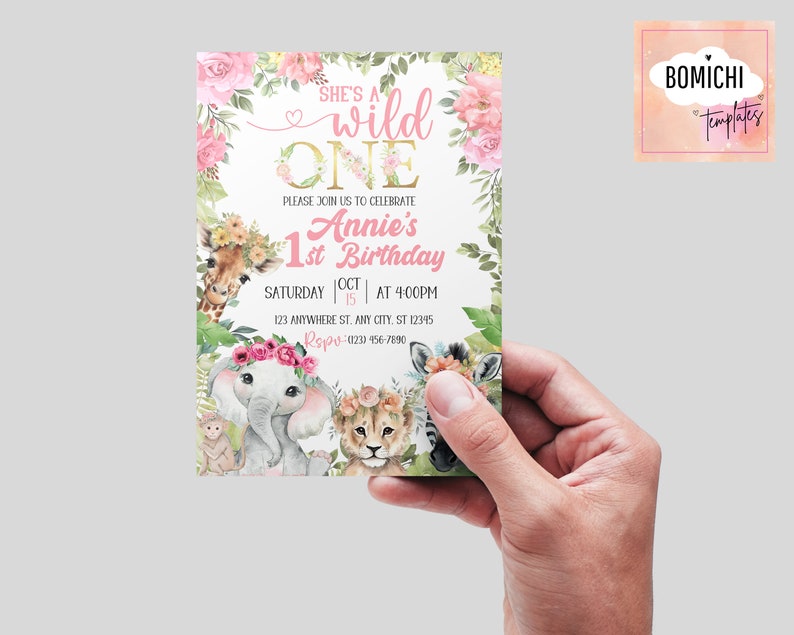 May include: A pink and gold first birthday invitation with a jungle animal theme. The invitation features a giraffe, elephant, lion, and zebra with floral accents. The text reads "She's a wild one Annie's 1st Birthday Saturday Oct 15 at 4:00pm 123 Anywhere St. Any City, ST 12345 Repu- (023) 456-7890"
