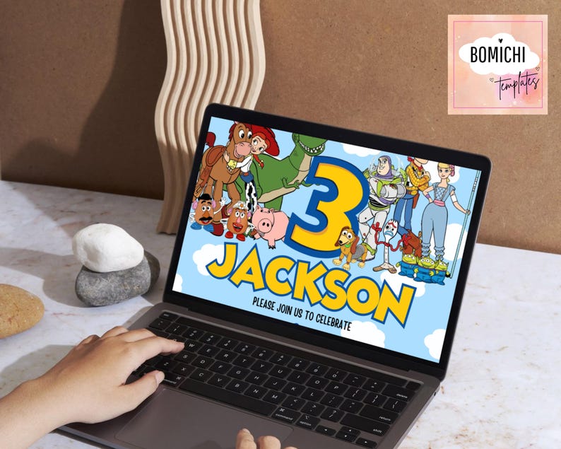 K&ouml;nnte beinhalten: Ein Laptop zeigt eine farbenfrohe Geburtstagseinladung mit der Zahl 3 und dem Namen "Jackson". Die Einladung zeigt Zeichentrickfiguren und den Text "PLEASE JOIN US TO CELEBRATE". Der Laptop befindet sich auf einer wei&szlig;en Oberfl&auml;che.