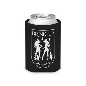 Puede incluir: Un enfriador de latas negro con un gr&aacute;fico blanco de dos brujas, una luna creciente y estrellas. El texto "DRINK UP WITCHES" se muestra en blanco, en arco. Dise&ntilde;ado para una lata de bebida est&aacute;ndar.