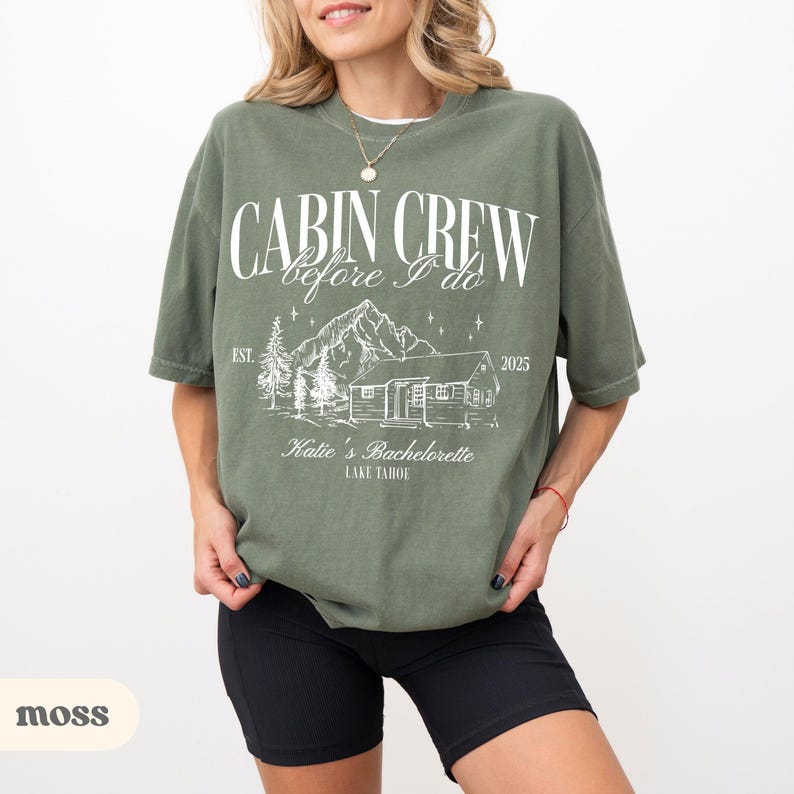 May include: A green t-shirt with white text that reads 'Cabin Crew before I do Est. 2025 Katie's Bachelorette Lake Tahoe' with a cabin and trees illustration.