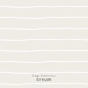Könnte beinhalten: Cremefarbener Hintergrund mit horizontalen, weißen, wellenförmigen Linien. Der Text "hej hanni" ist kursiv geschrieben, darunter das Wort "cream" in einer serifenlosen Schrift.