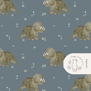 May include: A repeating pattern of watercolor-style Triceratops dinosaurs in shades of olive green and gray on a muted blue background. Small leaf and grass accents are scattered throughout. The design includes a logo with a bear and the text "hej ham smoky".