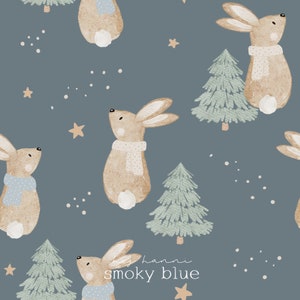 May include: A repeating pattern on a smoky blue background features illustrated bunnies wearing scarves, fir trees, stars, and dots. The text "by hanni smoky blue" is in the lower right corner. The bunnies are light brown with white tails.