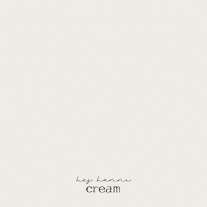 Könnte beinhalten: Cremefarbener Hintergrund mit einem dezenten Tupfenmuster. Die Wörter "hey hanni" sind in einer zarten Schriftart über dem Wort "cream" in einer einfachen serifenlosen Schrift geschrieben.