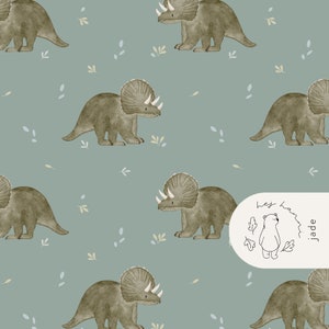 May include: A repeating pattern featuring watercolor illustrations of triceratops dinosaurs in shades of green and brown, set against a muted teal background. Small leaf and plant accents are scattered throughout the design. The lower right corner has a white oval with a bear illustration and the text "hey ham jade".