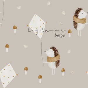 Könnte beinhalten: Ein nahtloses Muster mit beigefarbenem Hintergrund, braunen Igeln, weißen Drachen mit goldenen Sternen und braunen Pilzen. Der Text "hey hanni beige" steht in der Mitte des Musters.