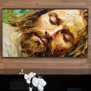 May include: A close-up painting of a man's face with his eyes closed. The painting is done in a painterly style with thick brushstrokes and vibrant colors. The man has a long beard and is wearing a white shirt.