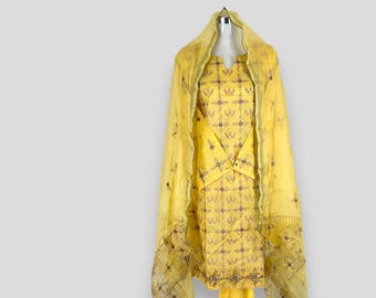 Puede incluir: Un vestido amarillo bordado con un dupatta transparente a juego. El vestido tiene un patrón floral y un escote en V.