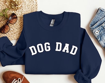 May include: A navy blue sweatshirt with white text that reads "DOG DAD" in a collegiate font.