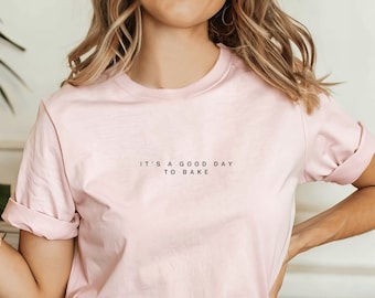 May include: A pink t-shirt with the text "It's a good day to bake" printed on the front.