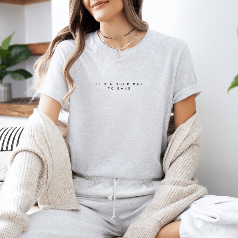 Pode incluir: Uma camiseta cinza com o texto "It's a good day to bake" estampado na frente.