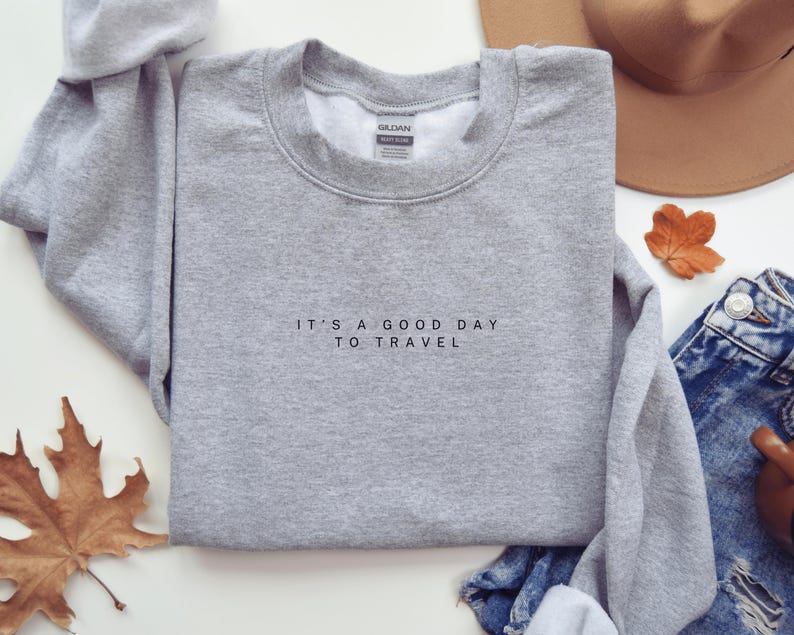 May include: Gray sweatshirt with the text "It's a good day to travel" printed on the front.