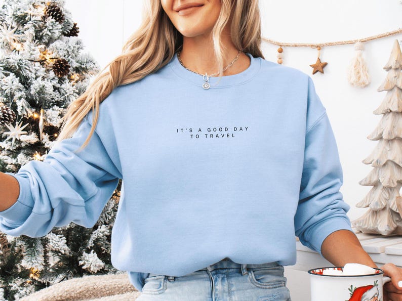 May include: A light blue sweatshirt with the text "It's a good day to travel" printed on the front.