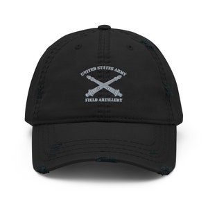 May include: A black distressed baseball cap with a gray embroidered logo that reads "United States Army Field Artillery" with two crossed cannons.