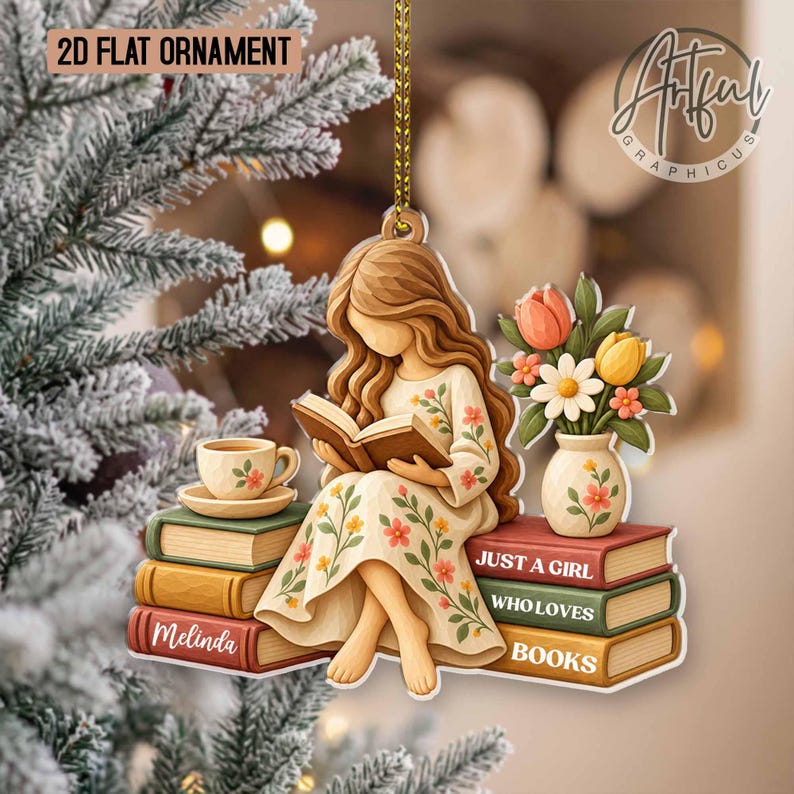 May include: A 2D flat ornament featuring a long-haired figure in a floral dress reading a book while sitting on a stack of books. The ornament includes a vase of flowers, a teacup, and text that reads "JUST A GIRL WHO LOVES BOOKS" and "MELINDA".