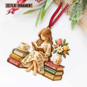 May include: A 2D flat ornament featuring a person with long brown hair reading a book while sitting on a stack of books. The person wears a cream dress with floral patterns. The ornament includes a teacup, a vase of flowers, and text reading Melinda and JUST A GIRL WHO LOVES BOOKS, suspended by a red ribbon.