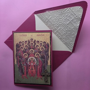 May include: A religious greeting card featuring an icon of angels and a baby, with gold accents and the text "H CYNAZIC TON ACOMATON". The card is paired with a burgundy envelope with a cross pattern.