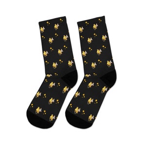 May include: A pair of black socks with a repeating pattern of yellow cartoon fish and gold stars.