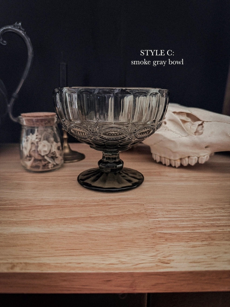 K&ouml;nnte beinhalten: Eine rauchgraue Glasschale mit einem Standfu&szlig;, die ein strukturiertes Muster aus vertikalen Rillen und kreisf&ouml;rmigen Motiven aufweist. Der Text "STYLE C: smoke gray bowl" ist in Wei&szlig; &uuml;ber der Schale aus durchscheinendem Glas gedruckt.