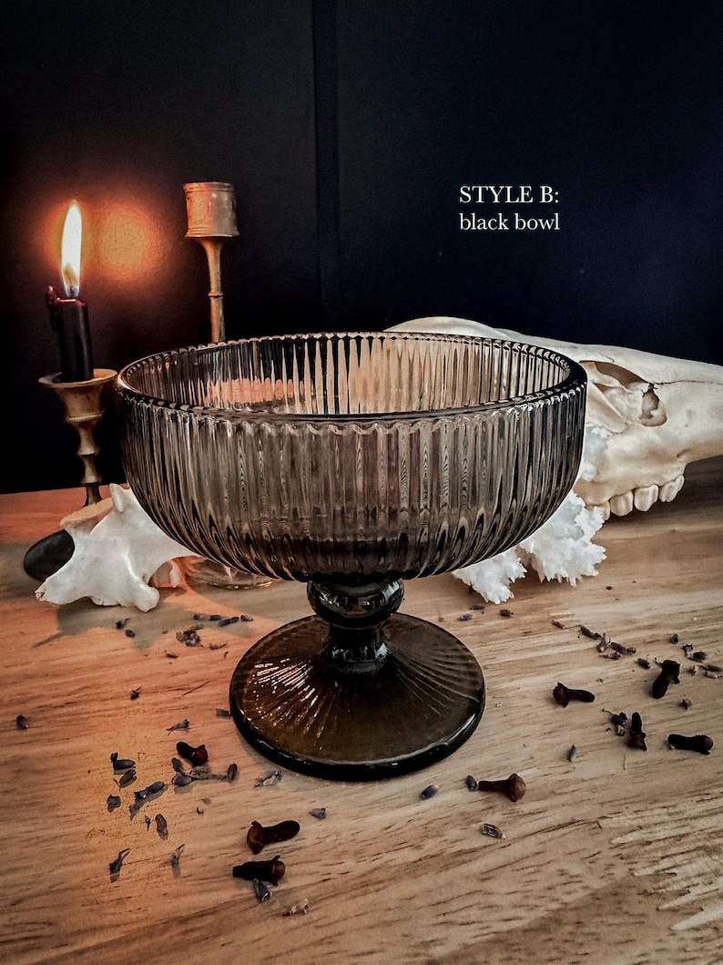 K&ouml;nnte beinhalten: Eine durchscheinende schwarze Glasschale mit vertikalem Rillenmuster, ausgestattet mit einem breiten kreisf&ouml;rmigen Rand, einem kurzen Stiel und einem runden Fu&szlig;. Der Text "STYLE B: black bowl" ist oben rechts im Bild in Wei&szlig; gedruckt.