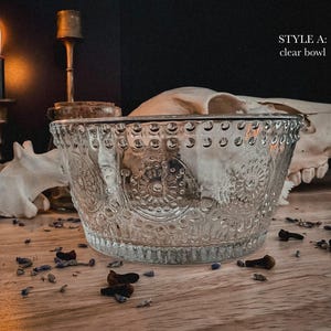 K&ouml;nnte beinhalten: Eine klare Glasschale mit einer strukturierten Oberfl&auml;che, gepr&auml;gten kreisf&ouml;rmigen Mustern und einem perlenartigen Rand. Der Text STYLE A: clear bowl ist in der oberen rechten Ecke des Bildes sichtbar und identifiziert das Produkt klar.