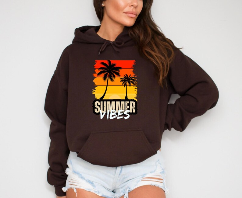 May include: A brown hooded sweatshirt with a graphic print of palm trees and a sunset. The text "SUMMER VIBES" is printed below the graphic.