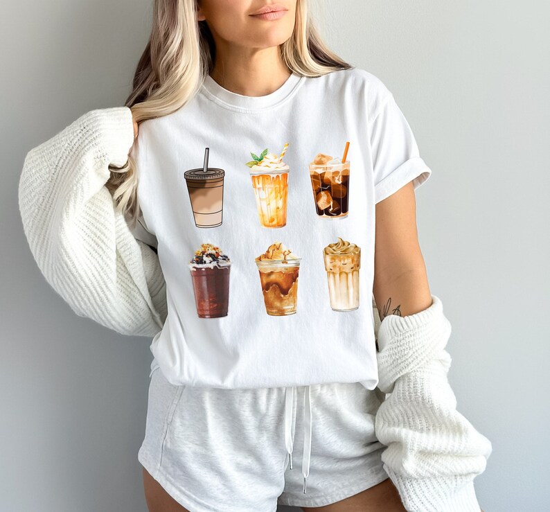 May include: White t-shirt with a graphic of six different iced coffee drinks. The drinks are illustrated in a watercolor style and include a variety of toppings, such as whipped cream, caramel, and chocolate.