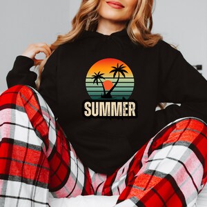 Puede incluir: Sudadera negra con un gr&aacute;fico de puesta de sol retro con palmeras y la palabra "SUMMER" en una fuente vintage.