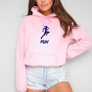 May include: Pink hoodie with a blue silhouette of a running woman and the word "RUN" in blue lettering.