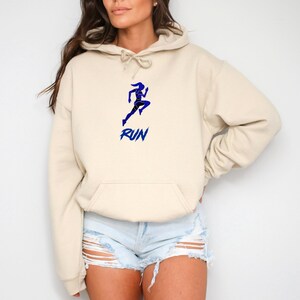 May include: A cream-colored hoodie with a blue silhouette of a running person and the word "RUN" in blue letters.