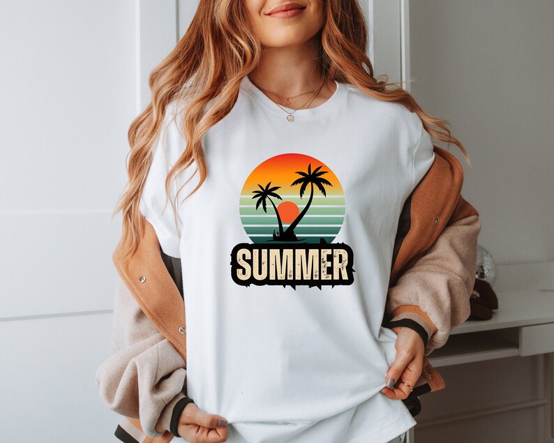 Peut inclure: T-shirt blanc avec un motif r&eacute;tro de palmiers et de coucher de soleil. Le motif est dans des tons d'orange, jaune, rouge, vert et bleu. Le texte "SUMMER" est imprim&eacute; sous le motif dans une police vintage.