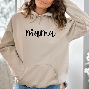 May include: A beige hoodie with a black heart and the word "mama" printed on the front.