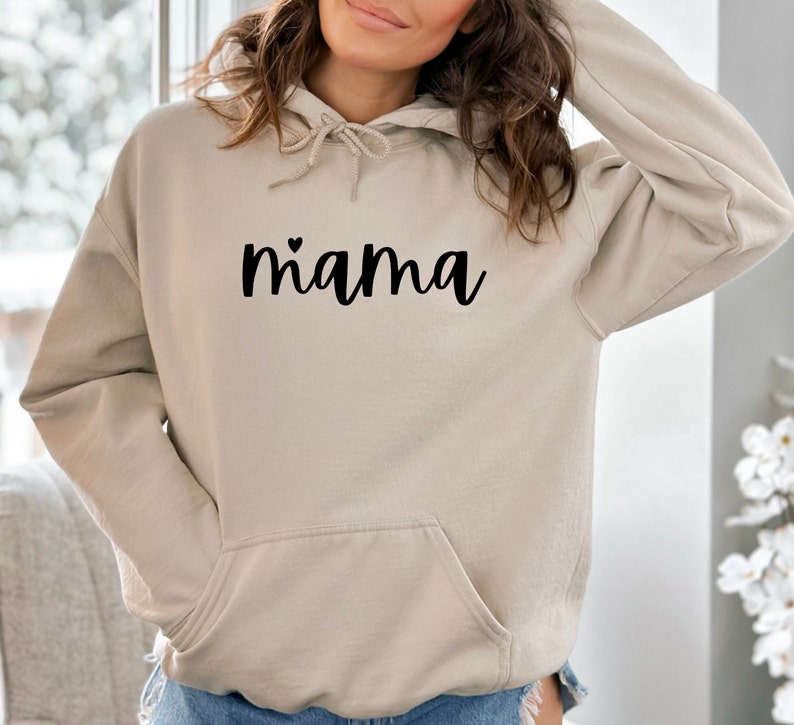 May include: A beige hoodie with a black heart and the word "mama" printed on the front.
