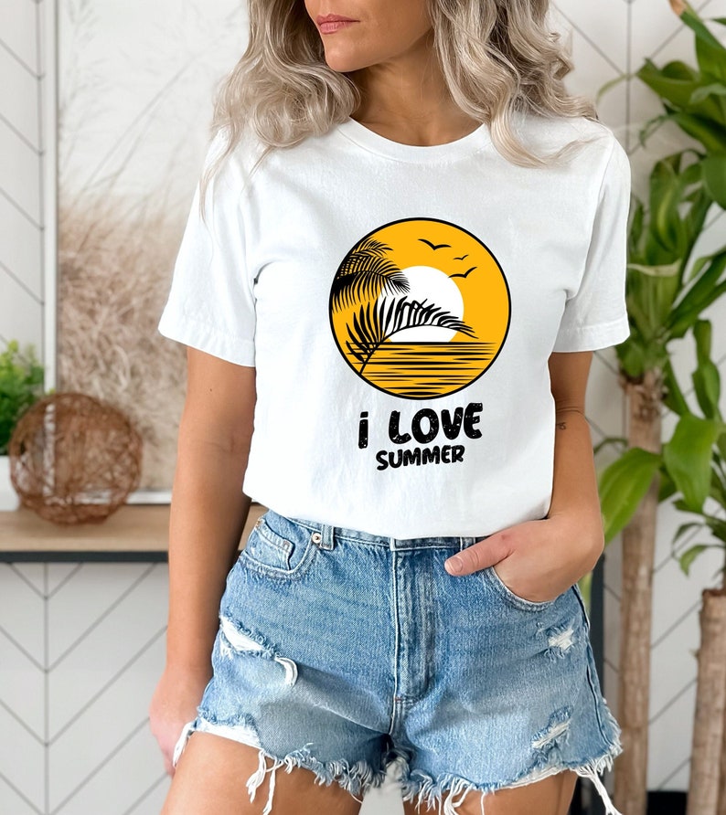 May include: White t-shirt with a yellow circle graphic of a palm tree, sun, and birds. The text "i love summer" is printed below the graphic.