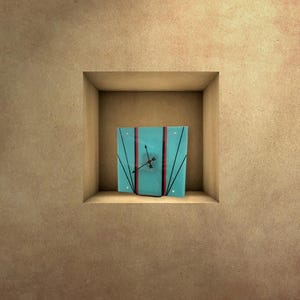 May include: A blue clock with black hands and red accents is displayed in a square niche in a beige wall.