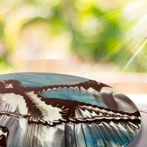 May include: A round, blue, white, and brown resin table top with a swirling, abstract design.