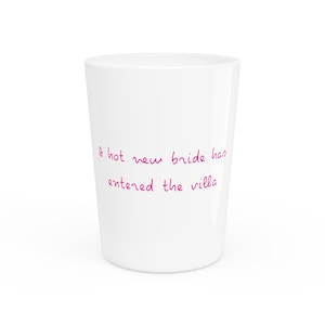 May include: White ceramic mug with the text "A hot new bride has entered the villa" written in pink.