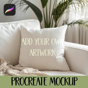 Può includere: Un cuscino quadrato beige con la scritta "ADD YOUR OWN ARTWORK" in bianco. Il cuscino è su un divano bianco con una coperta beige. Le parole "PROCREATE MOCKUP" sono in basso nell'immagine.
