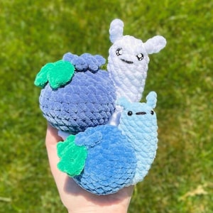 May include: Three crocheted plush toys shaped like snails. One is white, one is blue, and one is blue with green leaves.