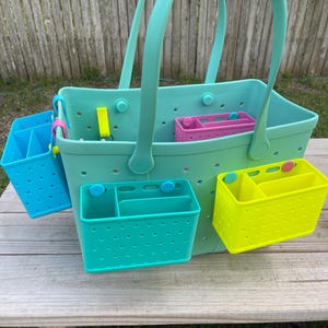 May include: A large, teal tote bag with matching teal handles and several colourful, removable organiser inserts. The inserts are blue, pink, and yellow. The bag and inserts are made of a durable, perforated material.