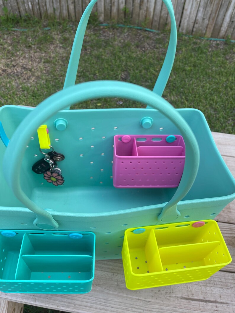 May include: A light blue tote bag with a handle, featuring a perforated design. Includes a pink and two other coloured organiser inserts. A set of keys with a flower charm hangs from the handle.